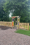 Children's play area with wooden structure and colorful panels in a park setting.